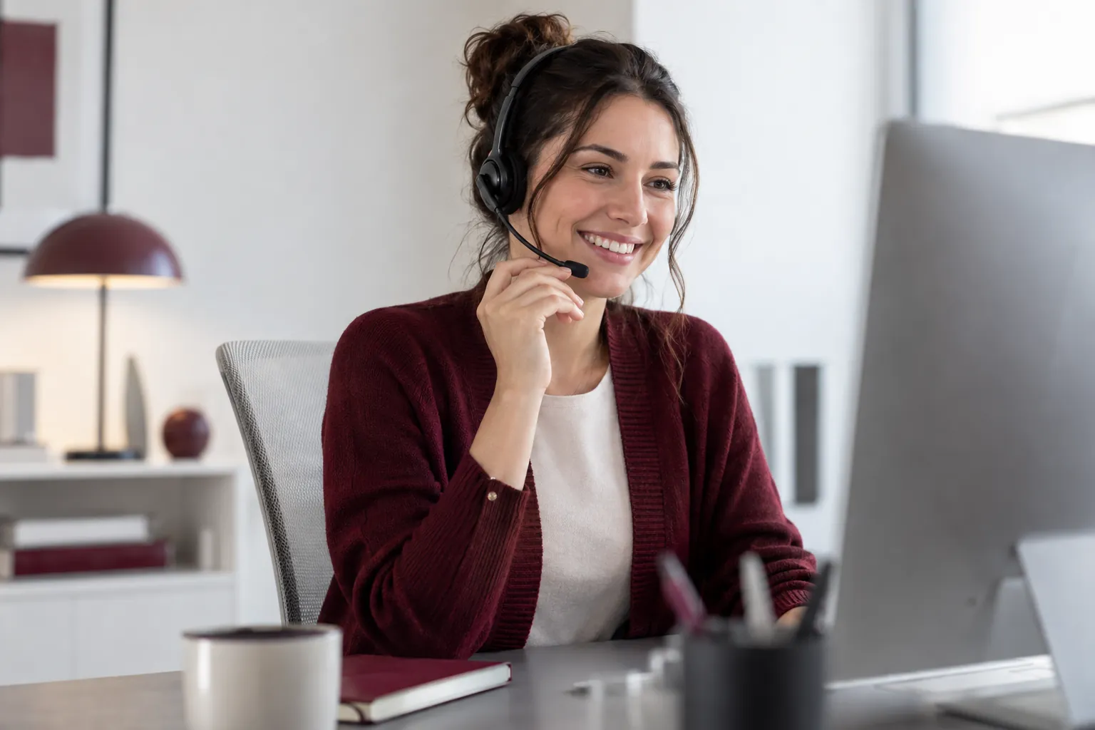 Profissional de atendimento usando um headset em seu espaço de trabalho.